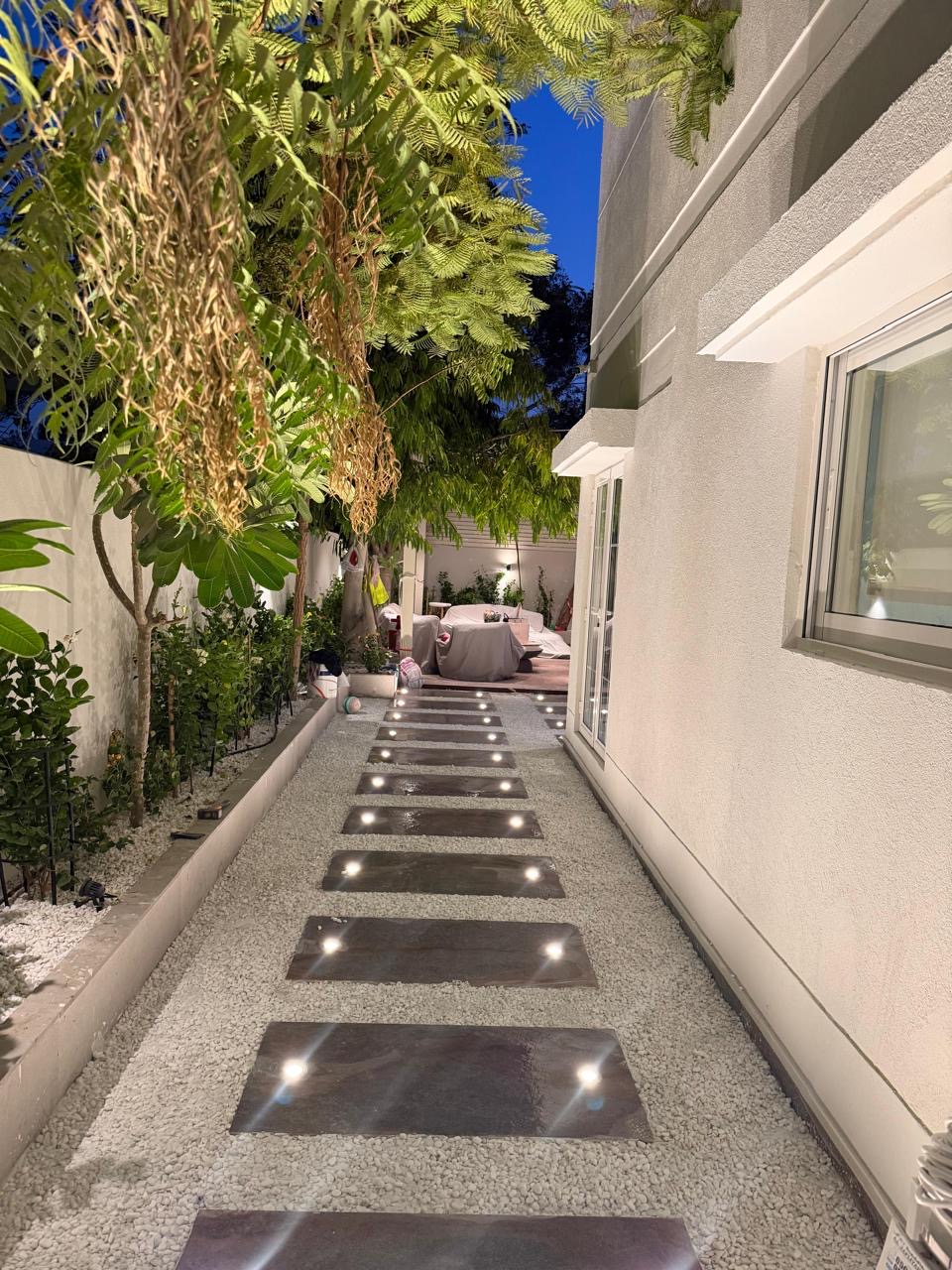 Side passage with lit stone pavers set in pebble.